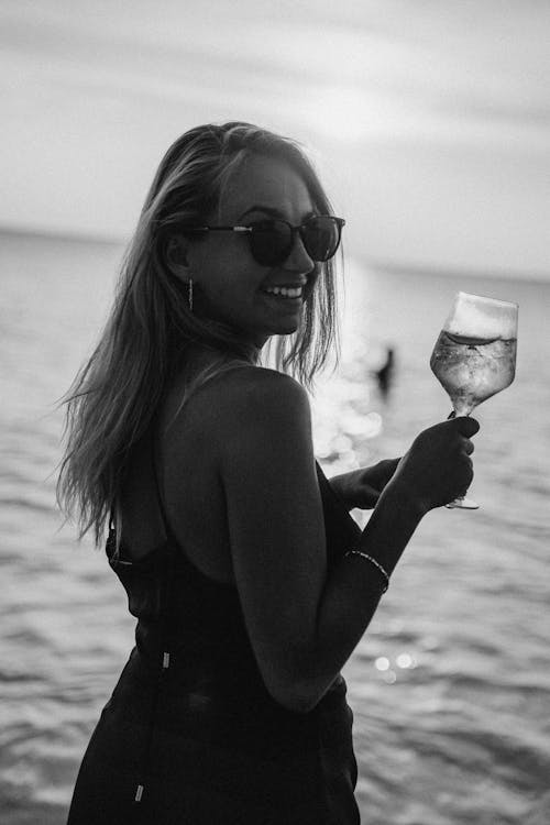 Black and White Portrait of Woman Standing on Beach with Glass of Champagne