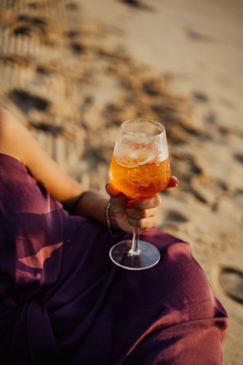Free A person holding a cocktail in a wine glass on a sunny beach afternoon. Stock Photo