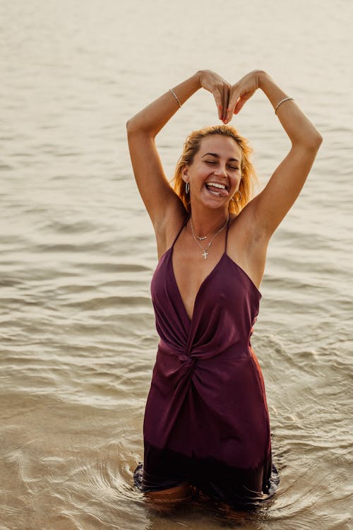 Free A Woman in Purple Spaghetti Strap Dress Standing on the Shore Stock Photo