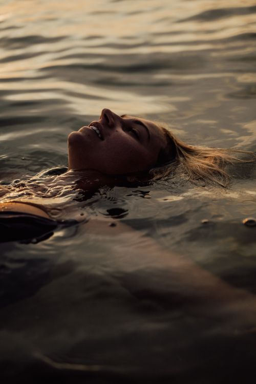 Free Captivating shot of a woman floating peacefully in the sea during sunset. Stock Photo