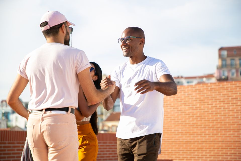 Two friends greeting each other warmly on a rooftop