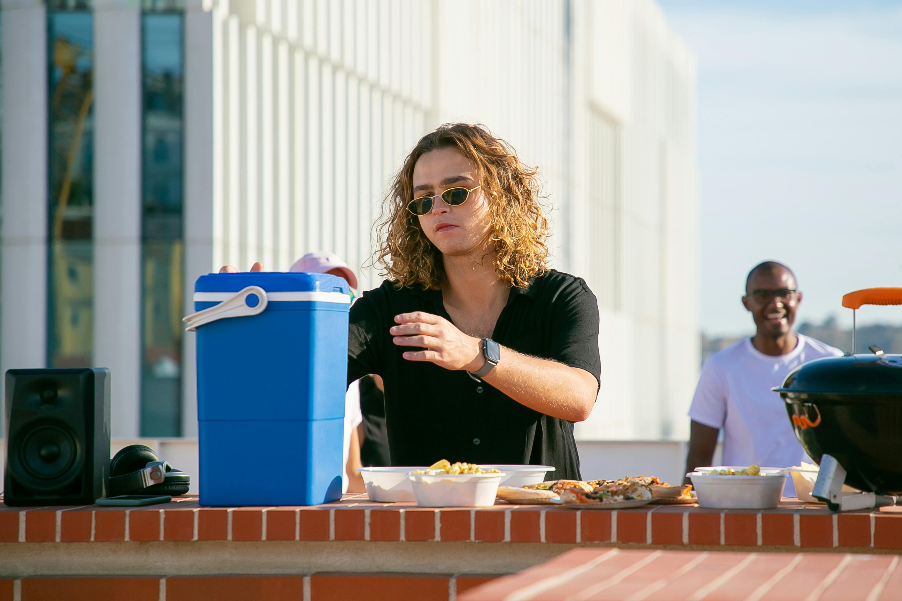 Casual rooftop barbecue scene with friends enjoying a sunny day in Portugal.