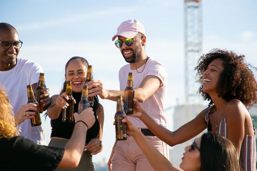Free A diverse group of friends cheers with beer bottles during an outdoor celebration. Stock Photo