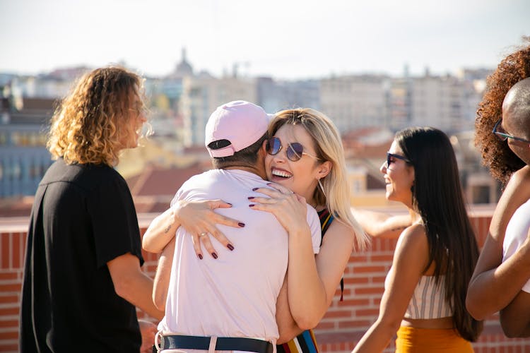 Happy Young People Hugging At Gathering