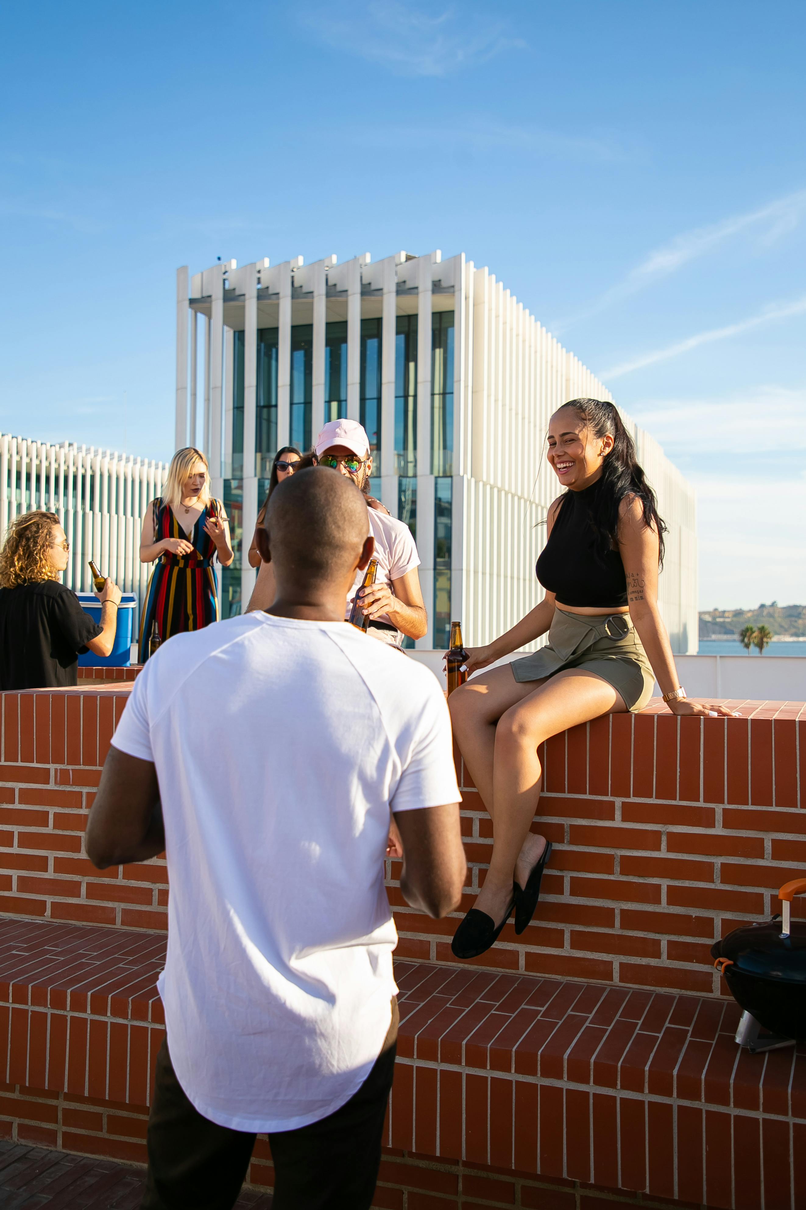 cheerful diverse friends having drinks on rooftop