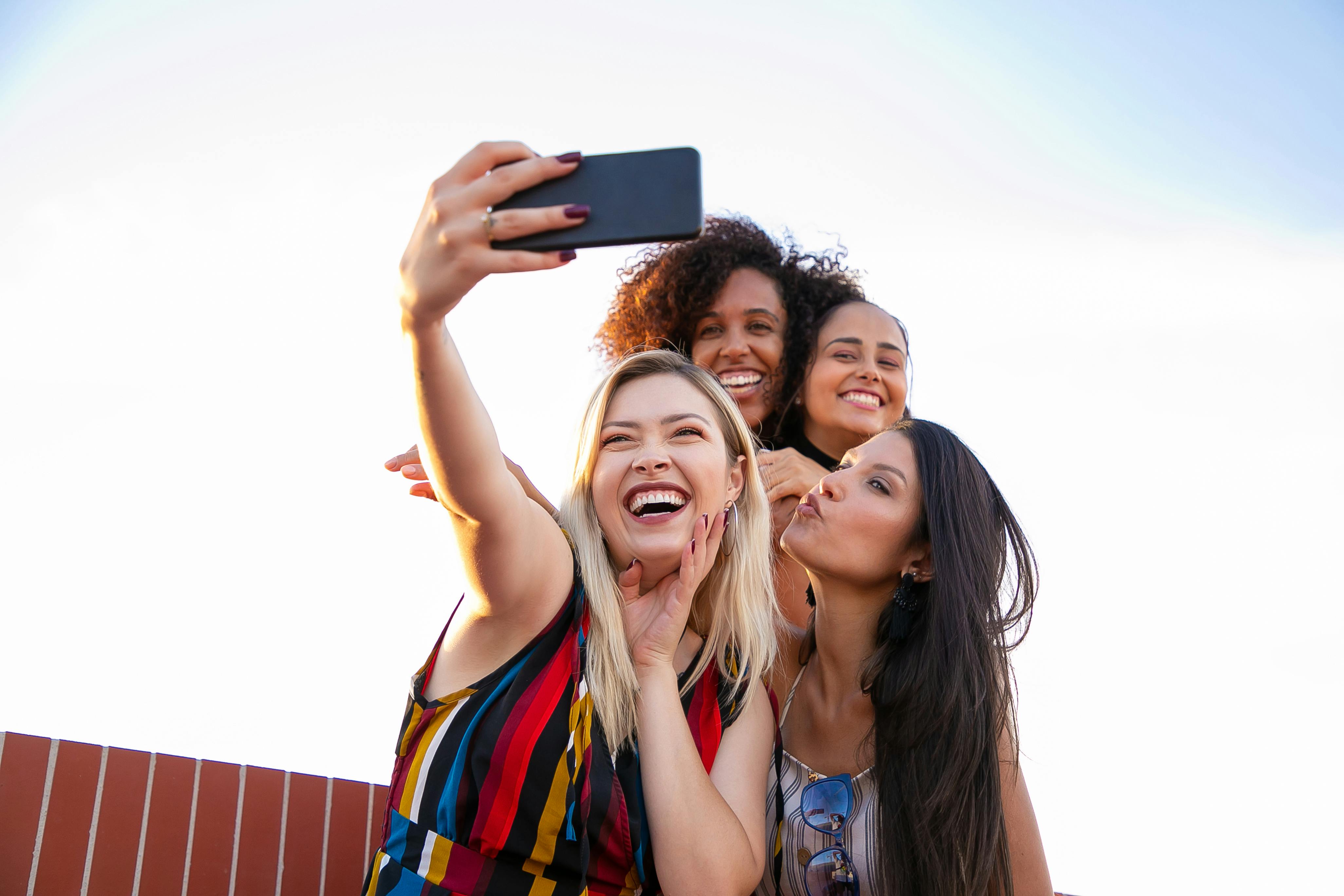 Free Photo | Girls taking selfie self portrait photos on smartphone.models  posing near blue wall in studio,female showing positive face emotions