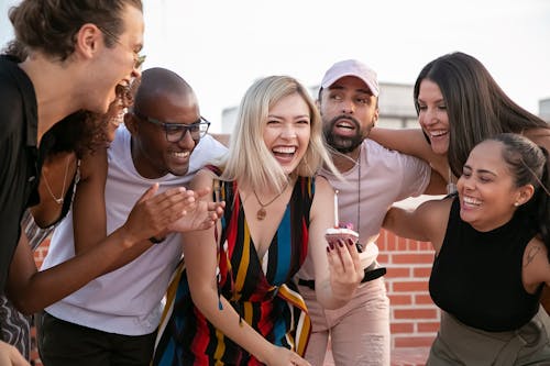 Free Excited young diverse friends celebrating birthday of cheerful woman on terrace Stock Photo