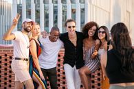 Faceless lady taking photo of positive diverse millennials during open air party