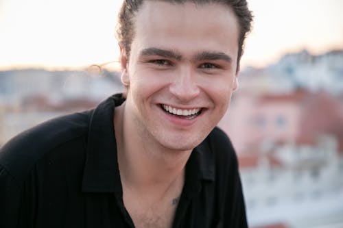 Handsome young male millennial smiling while resting on terrace