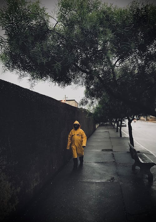 Man in Yellow Hoodie Walking on Sidewalk