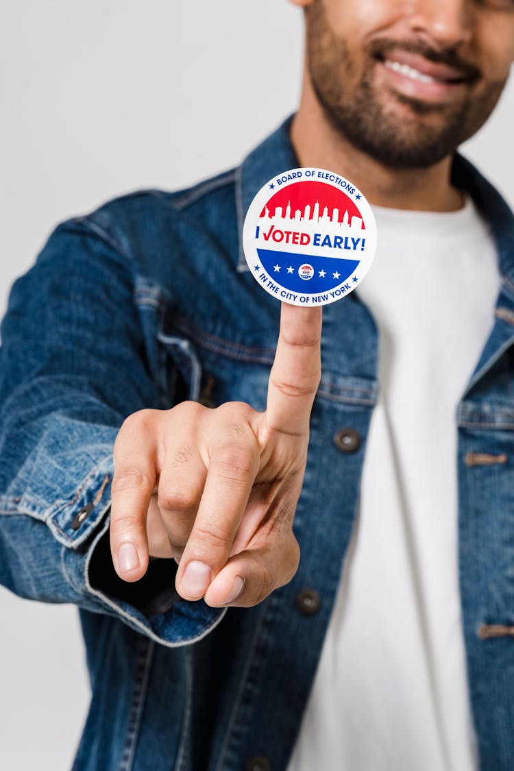 Man In Blue Denim Button Up Jacket Showing A Voting Sticker