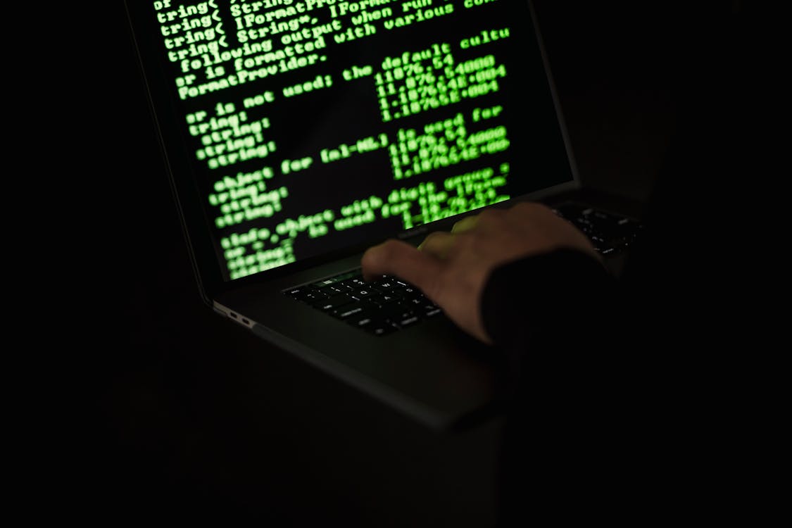 Free Crop hacker typing on laptop with information on screen Stock Photo