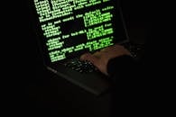 Crop hacker typing on laptop with information on screen