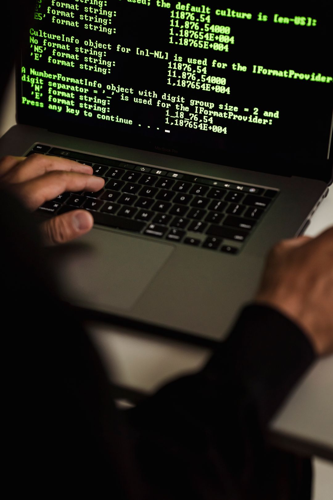 Hands typing exploit code on a laptop in a dark room