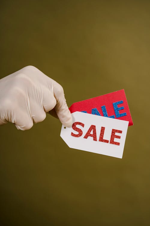 Person Holding Red And White Sale Tags
