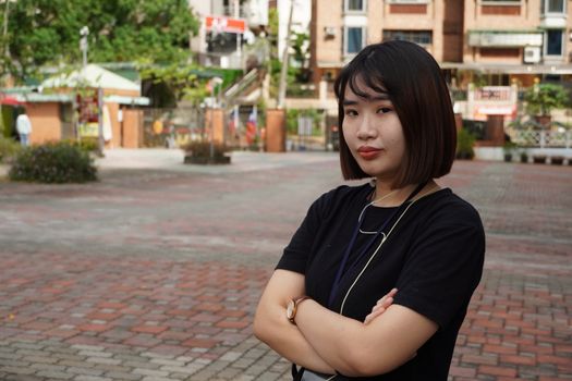 Portrait of a young Asian woman with short hair standing confidently outdoors in an urban area.