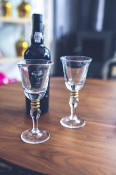 Two empty wine glasses and a bottle on a wooden table, creating a sophisticated, inviting atmosphere.