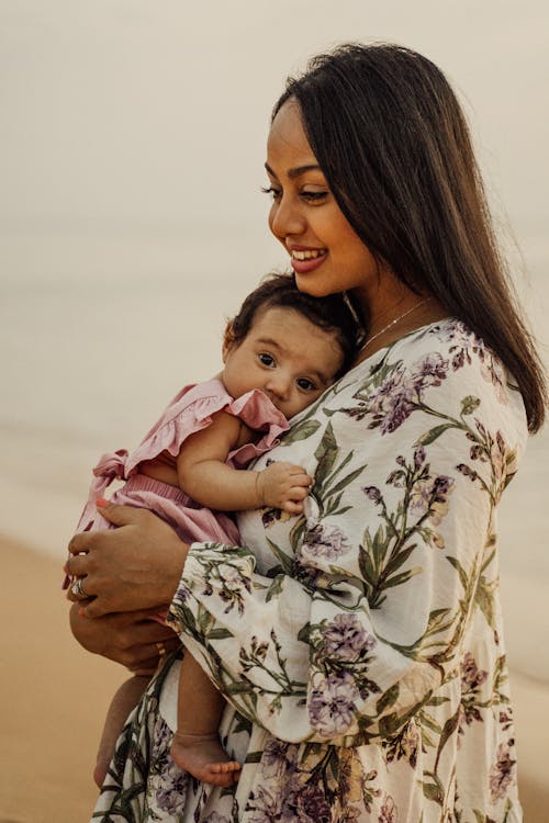 Wanita Dengan Kemeja Lengan Panjang Bermotif Bunga Putih Dan Hitam Menggendong Bayi Dalam Warna Pink Dan Putih