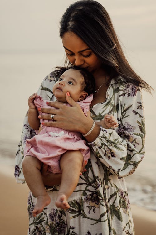Wanita Berkemeja Warna Putih Dan Hitam Menggendong Bayi Berkemeja Pink