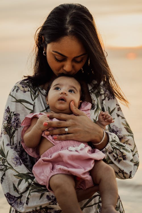 Wanita Dengan Kemeja Lengan Panjang Bermotif Bunga Hitam Putih Menggendong Bayi Dalam Warna Pink Dan Putih