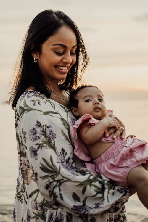 Woman in Floral Long Sleeve Shirt Carrying her New Born Baby 