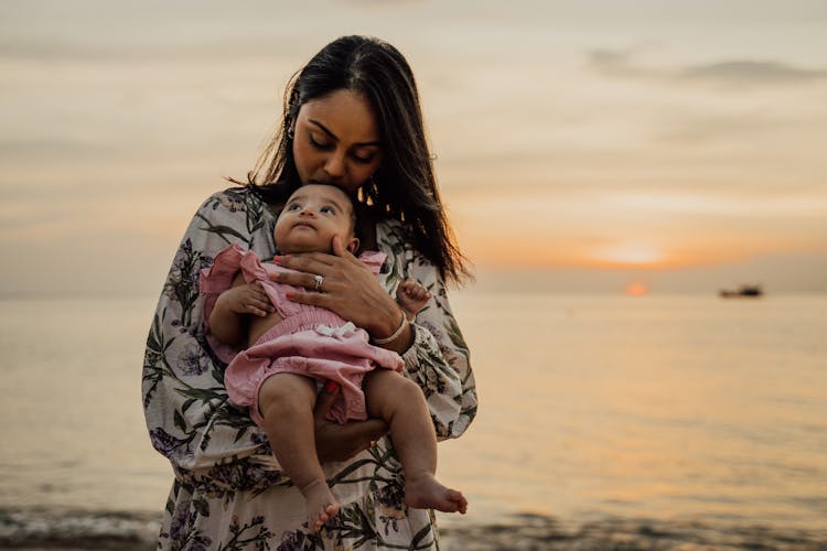 A Mother Kissing Her Daughter's Head During Golden Hour 