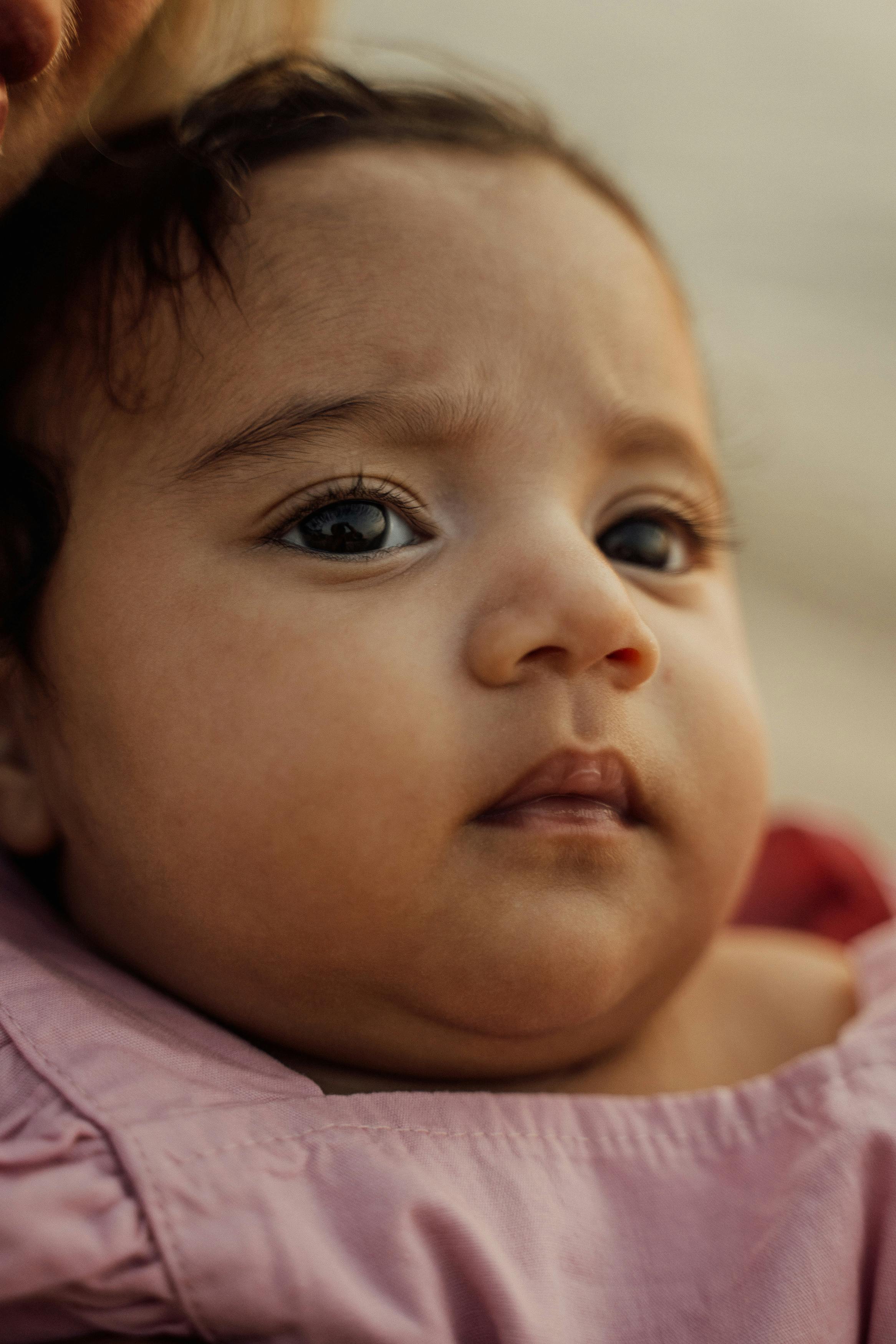 close up photo of a baby wearing a pink top