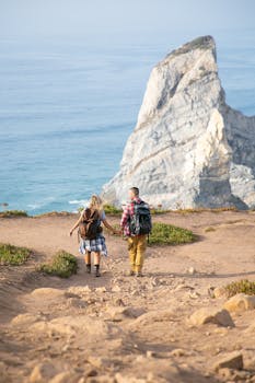 A couple hikes towards a stunning rocky coastline in Portugal, capturing the beauty of outdoor adventure.