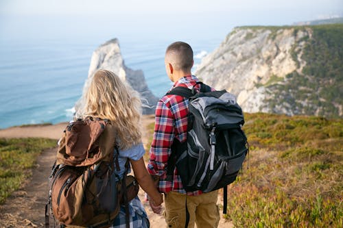 Backpackers Standing on Top of a Mountain while Holding Each Others Hands