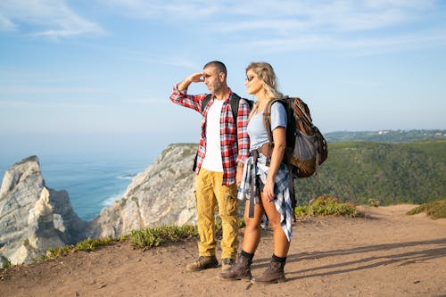 Uomo E Donna In Piedi Sulla Sabbia Marrone Vicino Al Corpo D'acqua