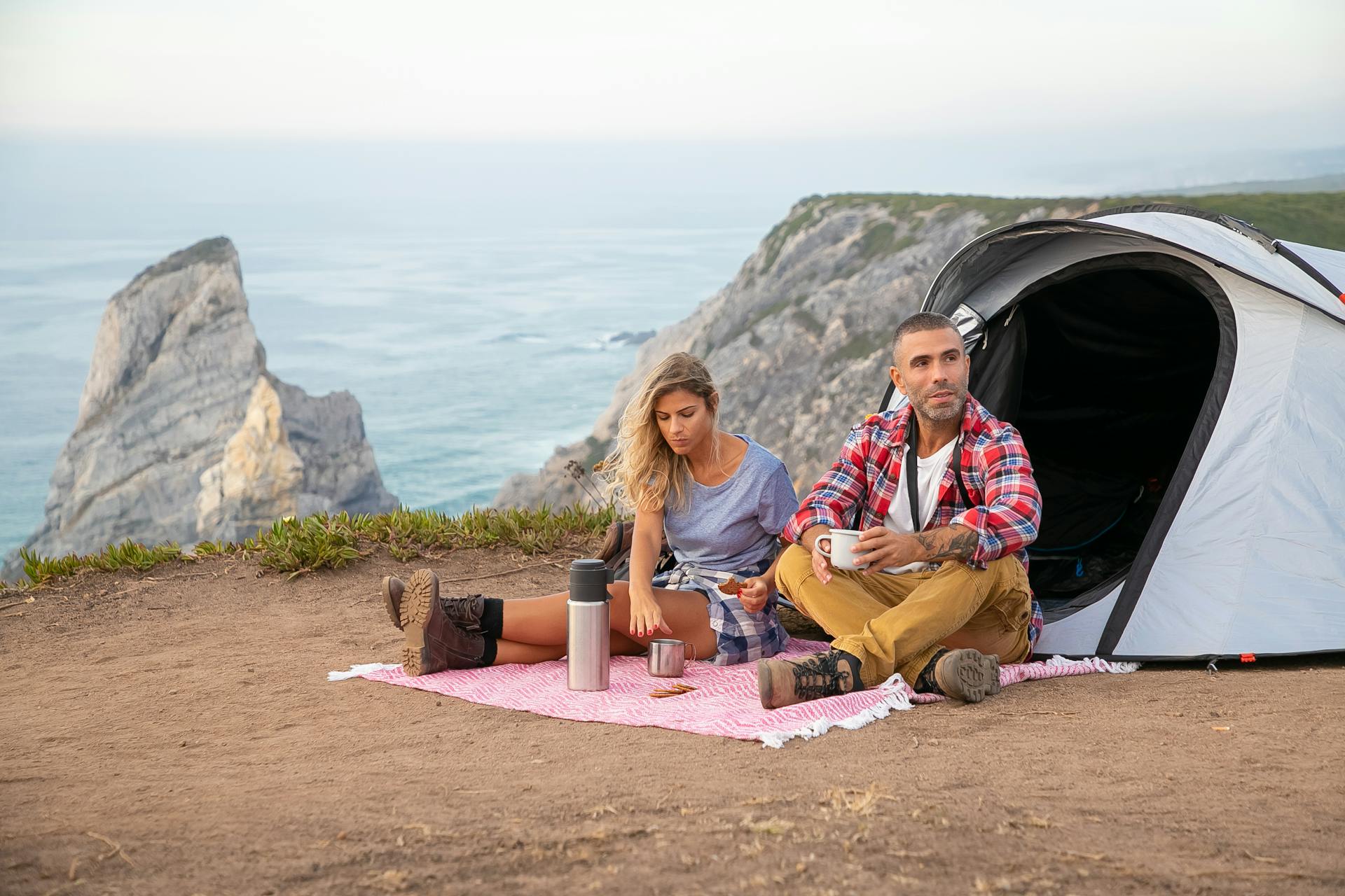 Man and Woman Resting on a Mountain Top while Eating Snacks