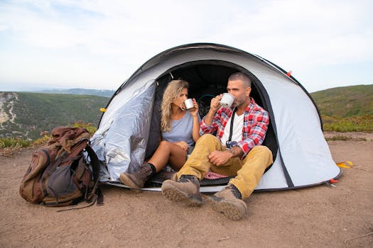 A couple enjoys coffee while sitting outside their tent with a scenic view, embodying a sense of adventure and relaxation.
