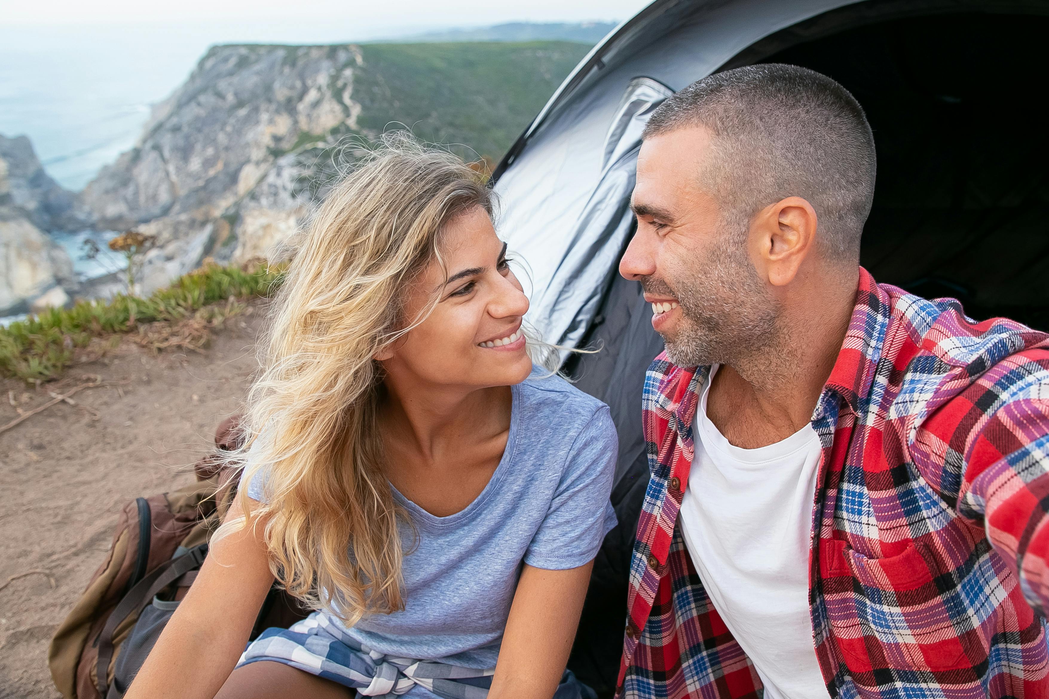 幸福的情侣在葡萄牙的悬崖边露营，微笑着享受大自然