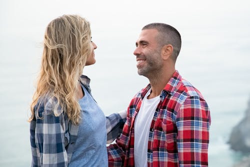 Uomo In Camicia Di Vestito Scozzese Rosso Bianco E Blu Che Bacia Donna In Giacca Di Jeans Blu Durante