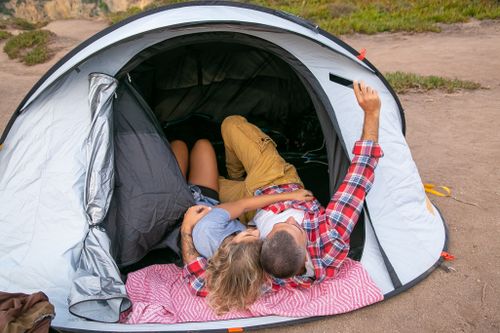 Free Romantic couple taking a selfie while relaxing in a tent surrounded by nature. Stock Photo