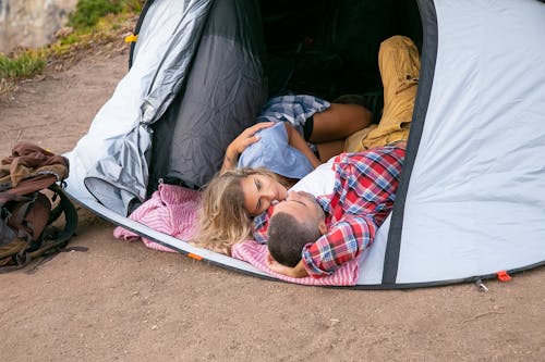 免费 躺在灰色和红色的帐篷里的红色和白色的格子衬衫的女孩 素材图片