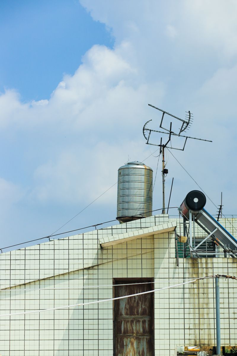 Rooftop water tank installation exposed to outdoor environment under open blue sky