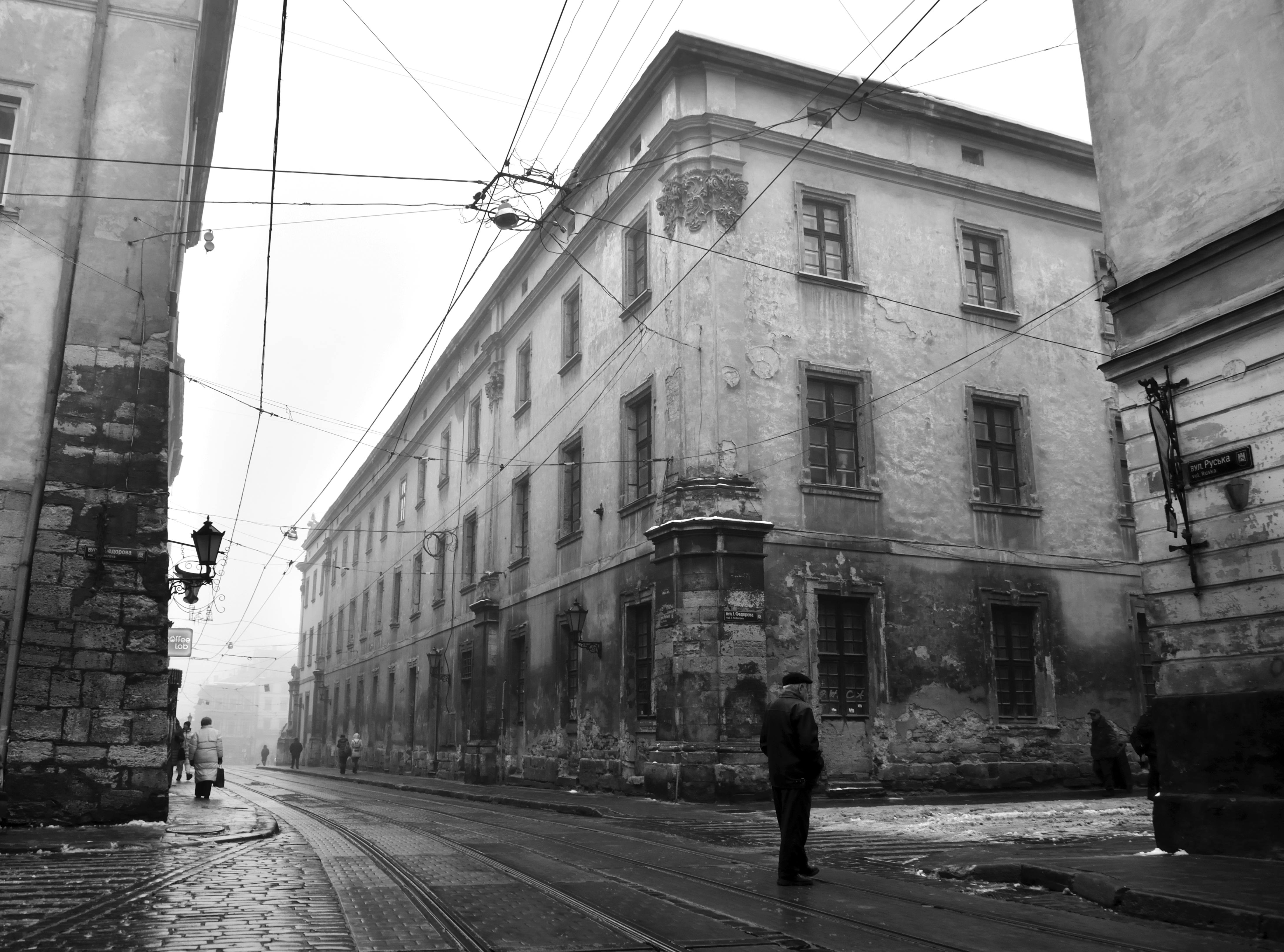 Black and white photograph of old buildings on a street in Lviv, Ukraine, with a man standing.