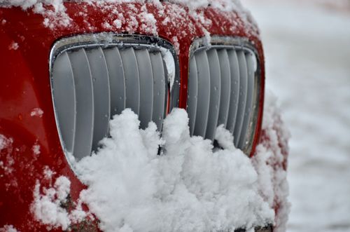 Free Detailed close-up of a snow-covered grille on a red car during winter. Stock Photo