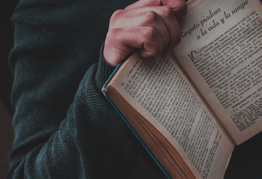 Close up of Mans Hand Holding a Book in Spanish