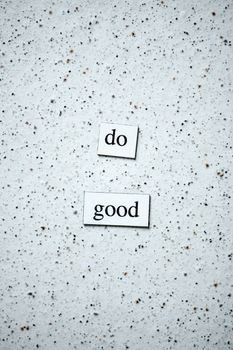 Inspirational words "do good" displayed on a textured surface, encouraging kindness and motivation.