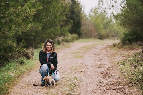 Free Smiling woman crouching with her dog on a scenic forest dirt path. Stock Photo