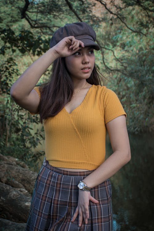 Woman in Yellow Top and Plaid Skirt Holding Hat 