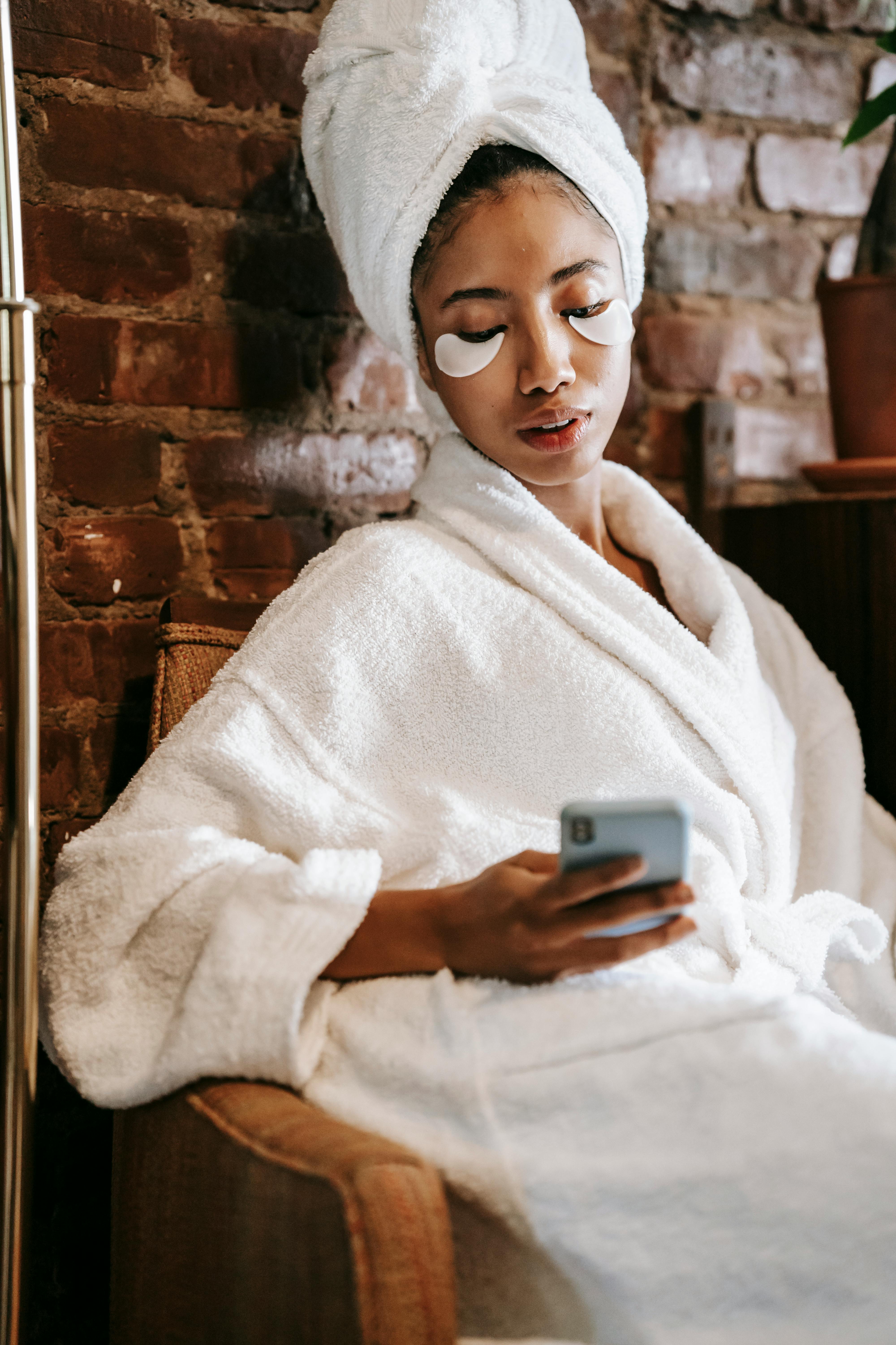 ethnic woman watching smartphone during procedure in spa center