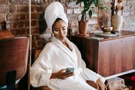 Ethnic woman browsing internet on smartphone in beauty salon