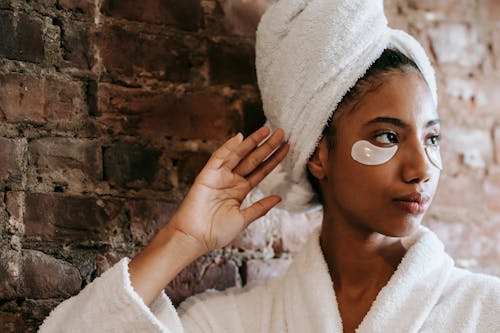 Charming ethnic woman with eye patches near brick wall