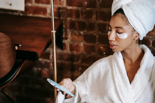 Ethnic woman touching screen on smartphone in beauty salon