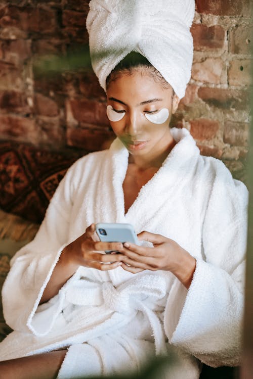 Focused ethnic woman chatting on smartphone in spa center