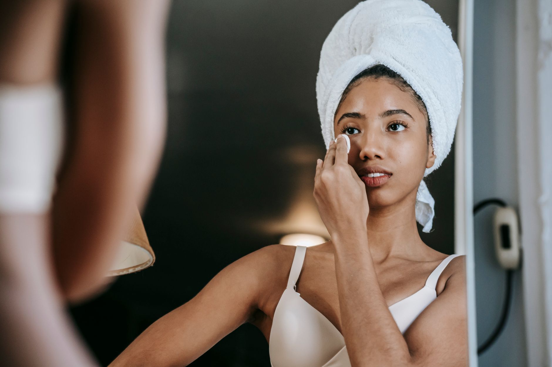Woman using a cotton pad to gently cleanse her face — gentle, fragrance-free cleansing is a key step in managing eyelid eczema
