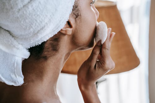 Crop ethnic woman with cotton pad during daily beauty routine